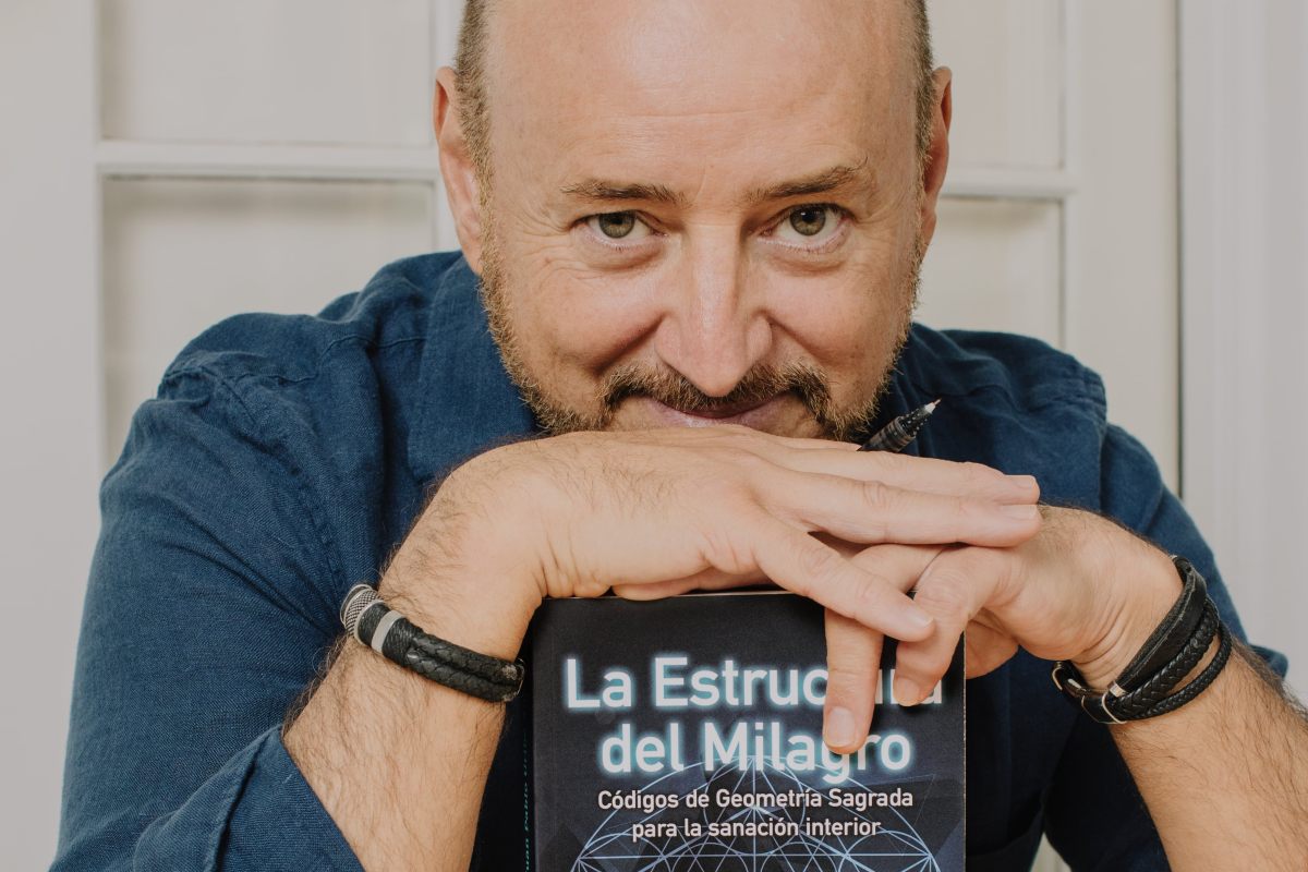 Photograph of the author Juan Pablo Uribe with his book entitled The Structure of the Miracle.