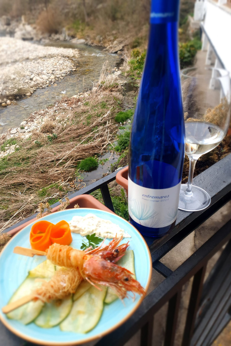 A bottle and a glass of white wine Entremares with a plate of seafood.