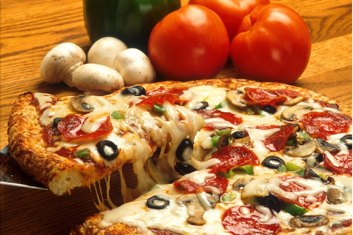 A freshly baked pizza with the ingredients in the background.