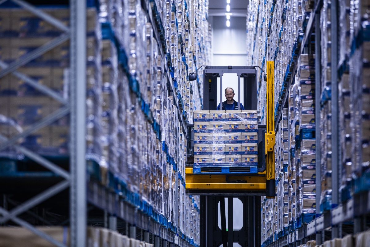 An operator with a mechanical platform transporting boxes in a Dachser warehouse.