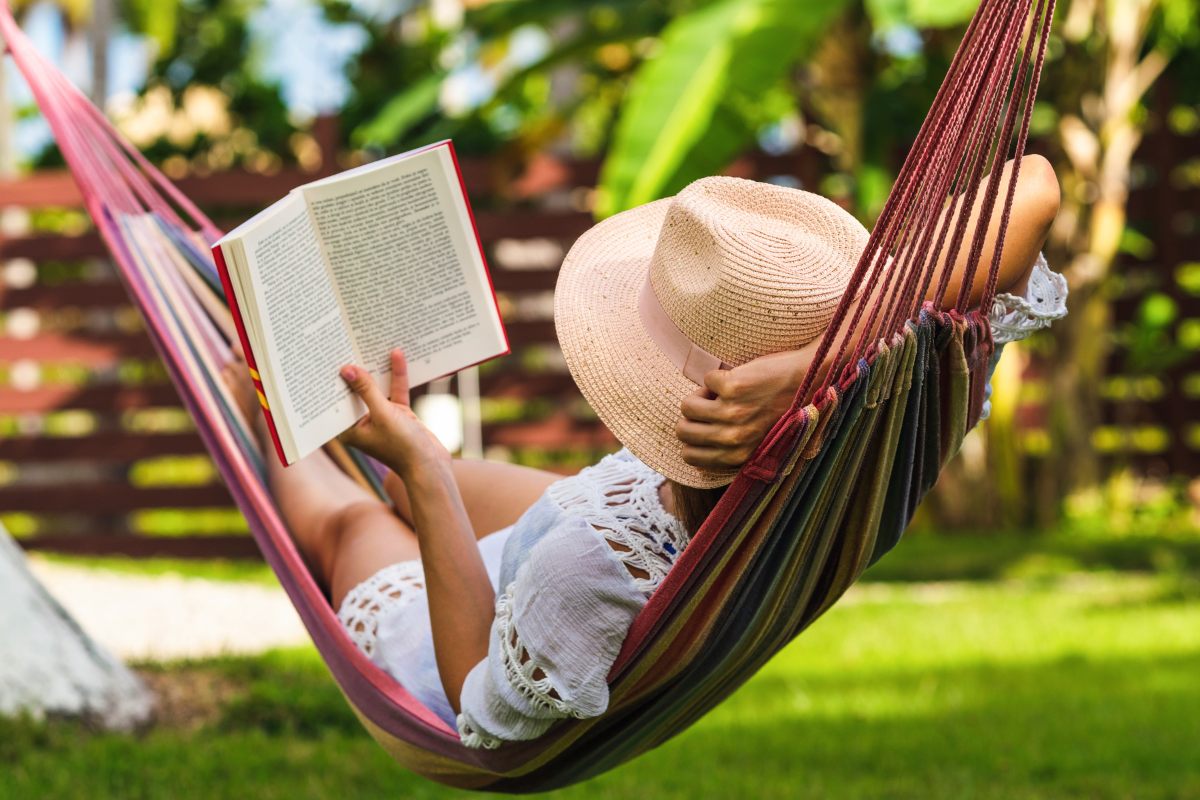 A woman slumbered in a hammock and read a book on a radiant summer day.