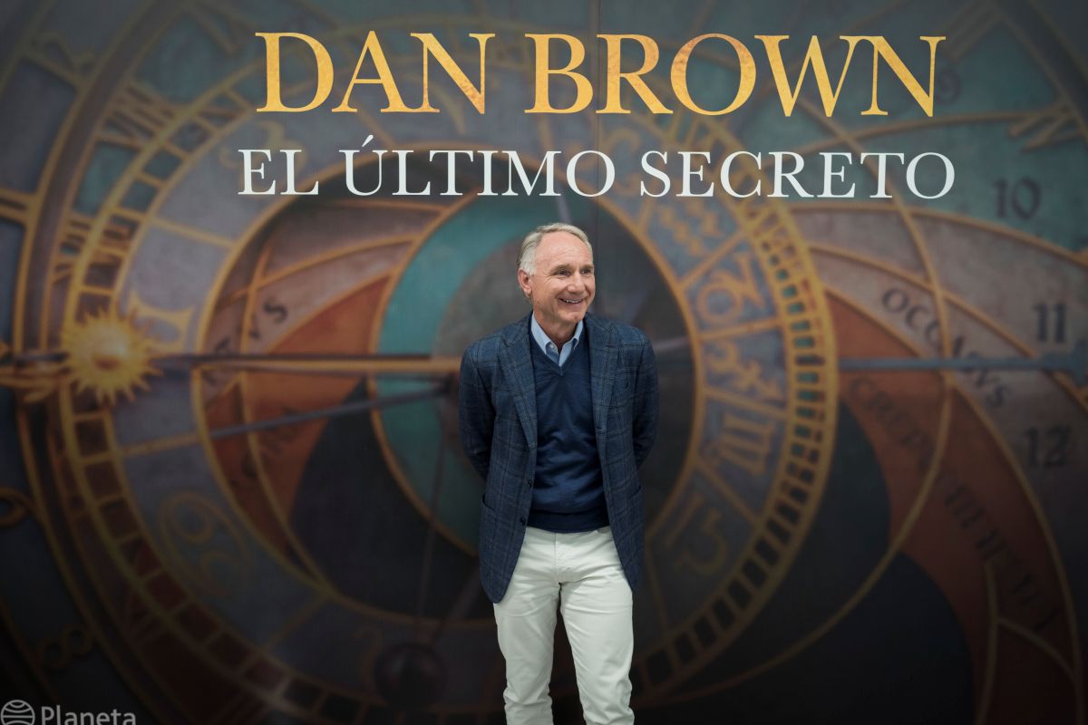 Portrait of Dan Brown, author, in front of the cover of his book entitled The Last Secret - courtesy of Liven Photography.