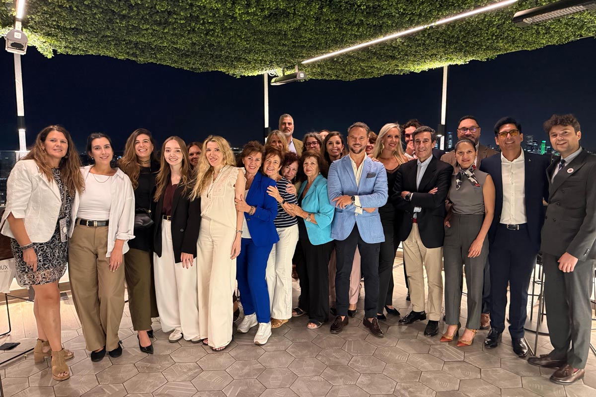 Group photo of the attendees — executives and travel managers — at the Consultia Business Travel event, smiling together on a rooftop terrace at dusk with the city skyline behind them.