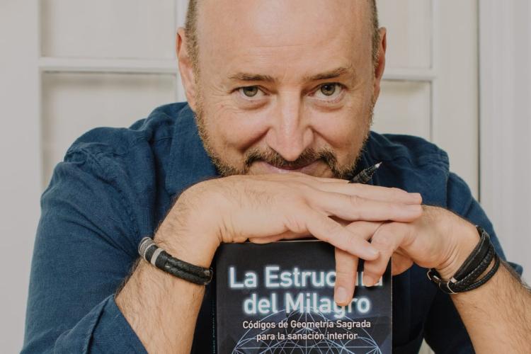 Photograph of the author Juan Pablo Uribe with his book entitled The Structure of the Miracle.