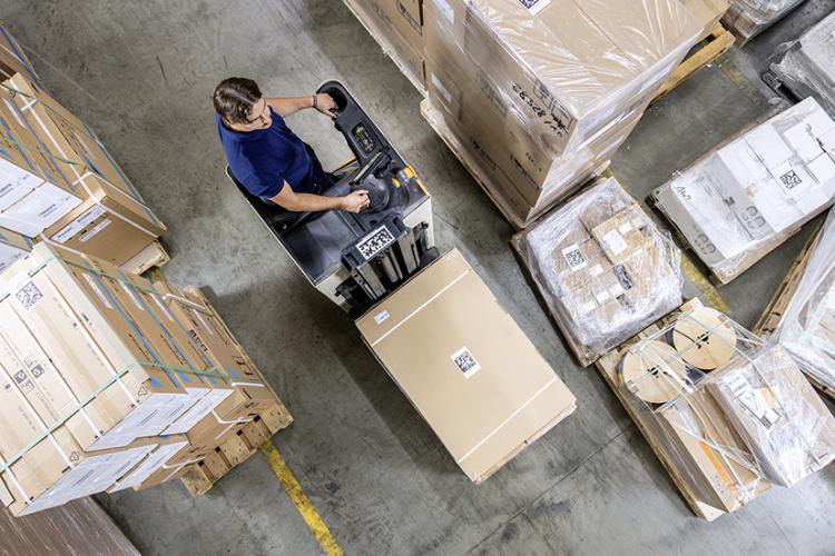 Man with vehicle transporting packages with the help of Dachser technology.