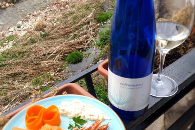 A bottle and a glass of white wine Entremares with a plate of seafood.