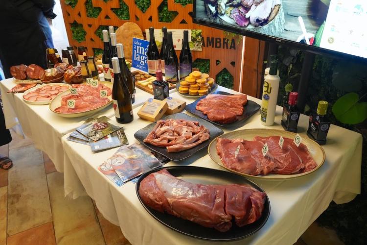 Display table featuring a variety of raw beef cuts, cured meats, wine bottles, olive oil, and regional food products at a Ternera Asturiana promotional event.