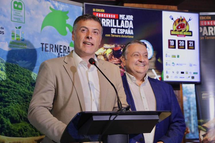Brasas del Narcea mayor addresses an audience at a podium during a Ternera Asturiana promotional event, with competition branding displayed on screens behind him.