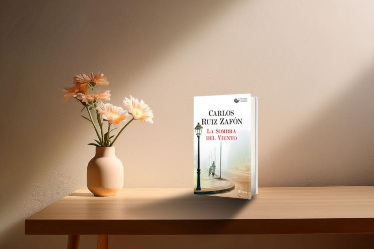 A modern desk with a vase and a copy of the book titled: The Shadow of the Wind.