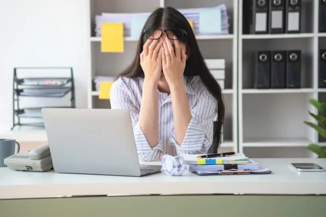 Concepto de síndrome de burnout con una mujer de negocios que se siente incómoda trabajando; el cual es causado por el estrés, acumulado por un trabajo infructuoso y por no descansar lo suficiente.