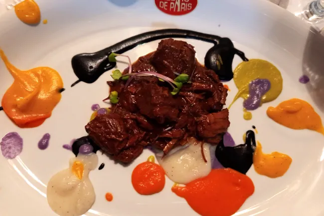 Un plato de estofado de ternera con pinturas del chef, del chef Roberto Capone.