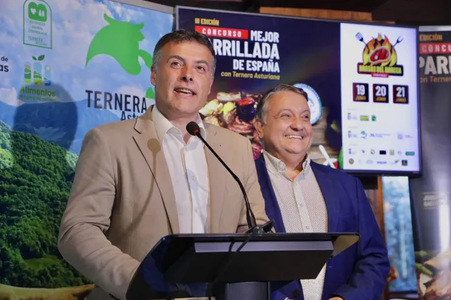 Brasas del Narcea mayor addresses an audience at a podium during a Ternera Asturiana promotional event, with competition branding displayed on screens behind him.