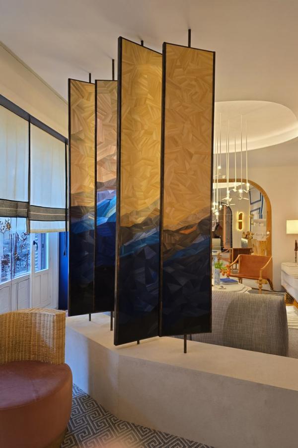 A four-panel sculptural screen mounted on floor-to-ceiling rods, created by Rubén Fabuel.