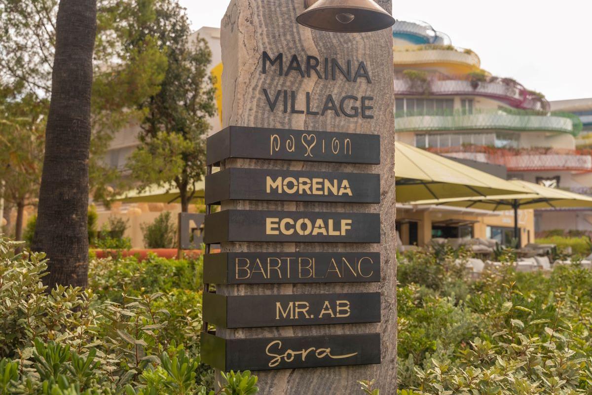 Entrada a Marina Village con la lista de tiendas y restaurantes en el recinto.